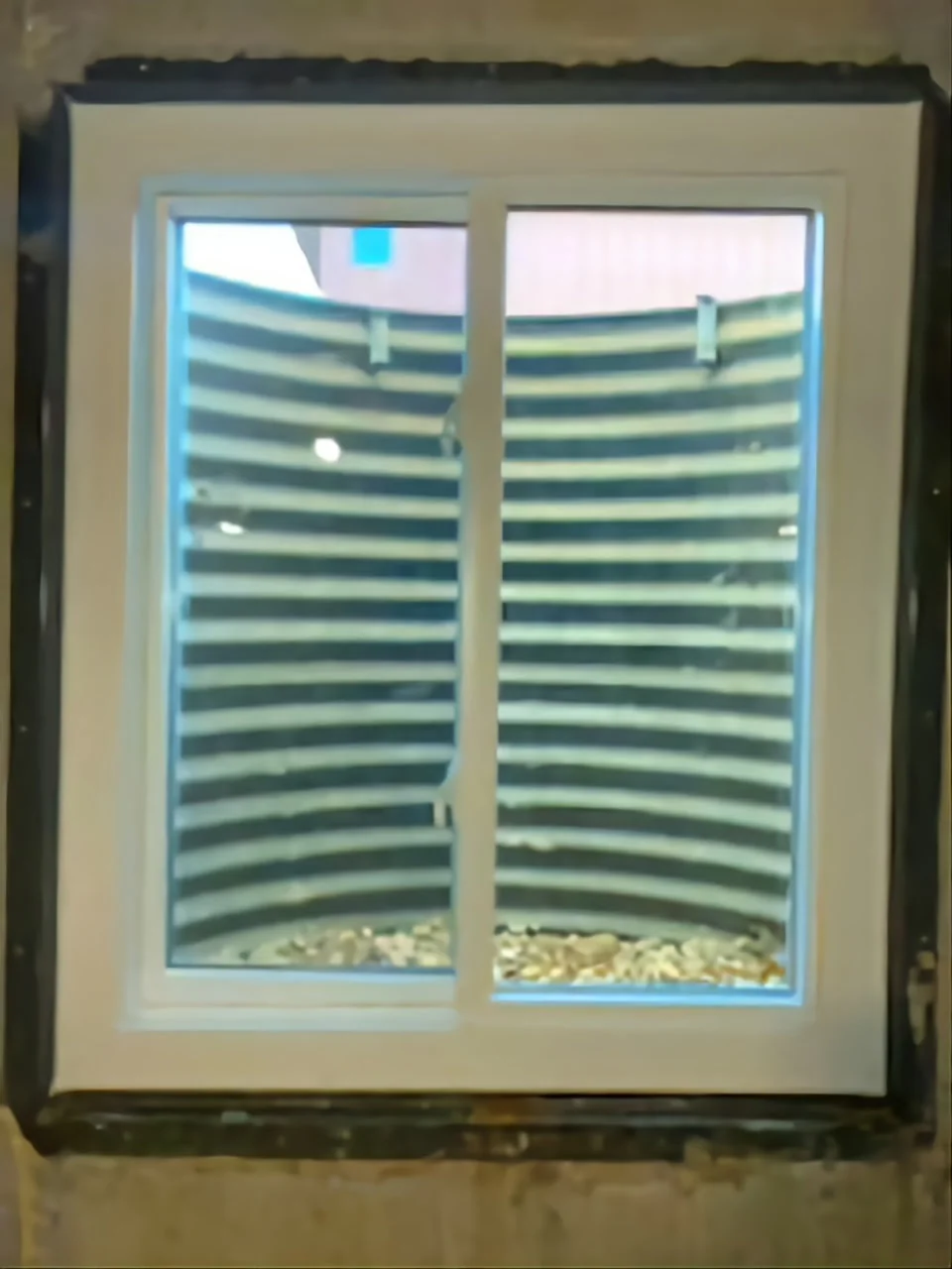 Interior view of basement window looking out through galvanized well