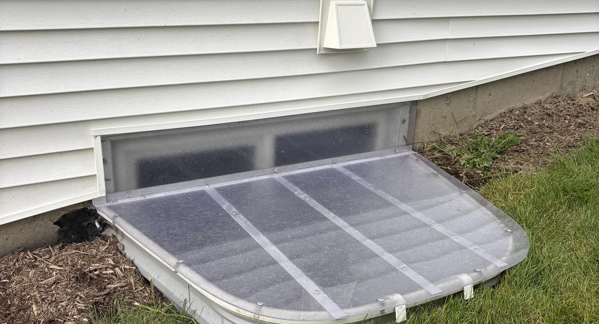 Clear Lexan window well cover custom fitted to a large egress window well on a Chicago-area home