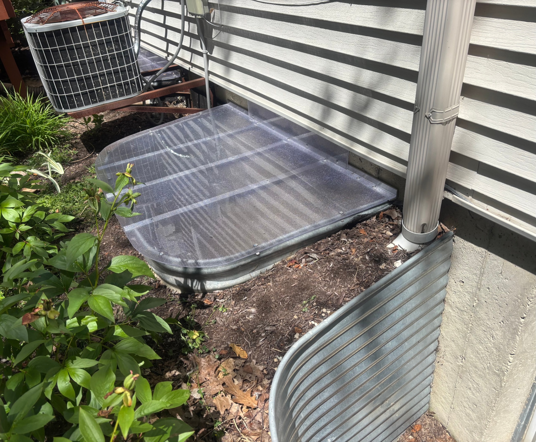 Custom clear window well cover on rectangular galvanized well next to AC unit