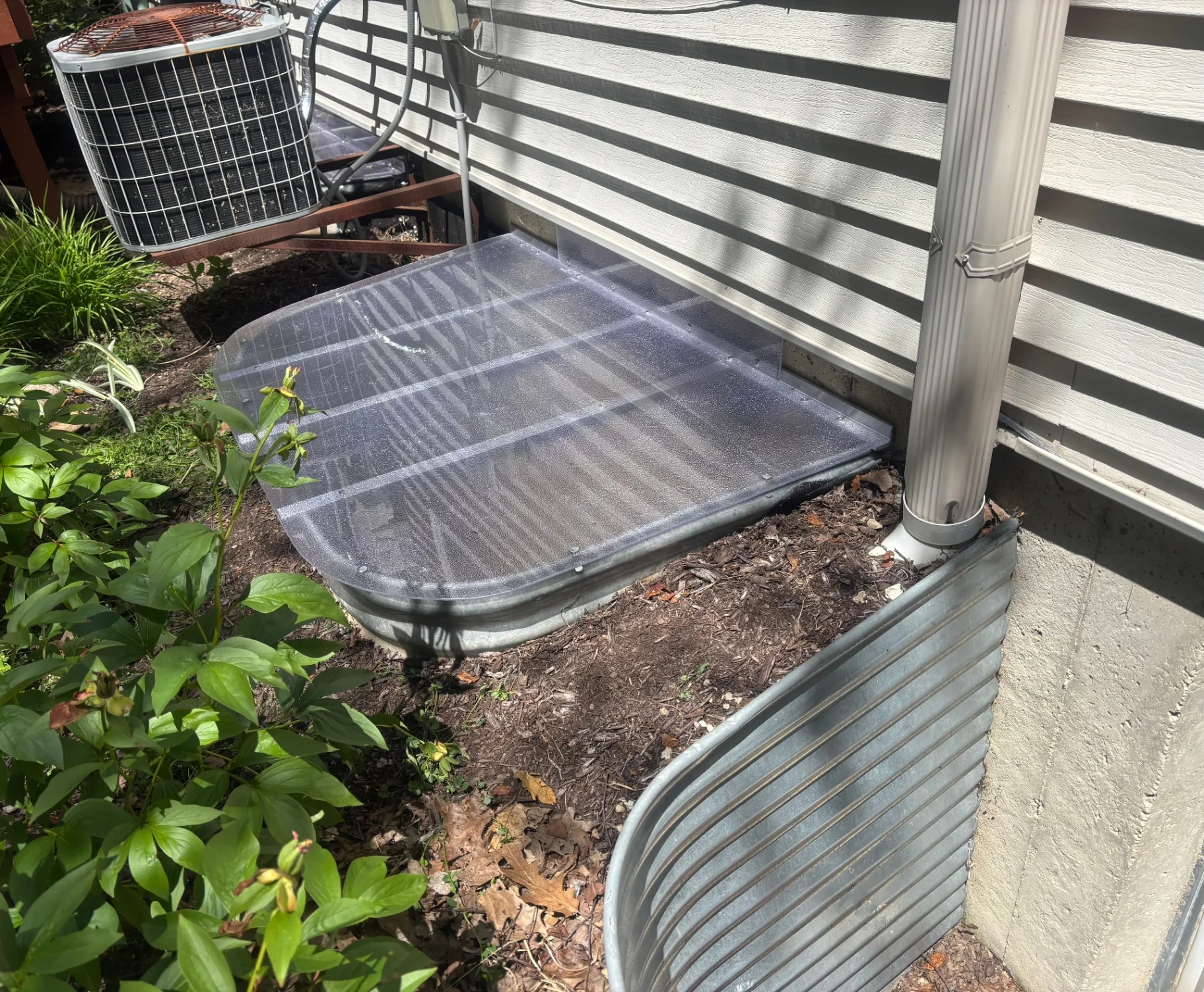 Custom clear window well cover on rectangular galvanized well next to AC unit