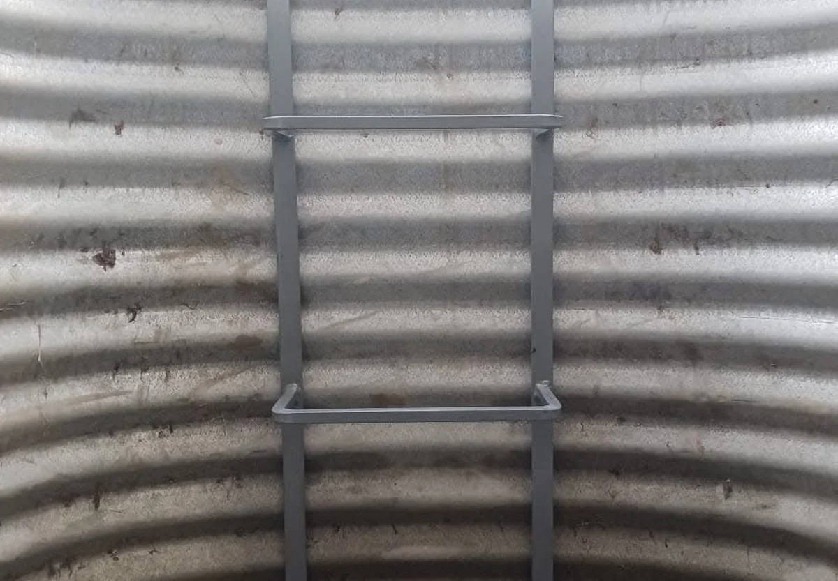 Close-up of a code-compliant egress ladder mounted inside a galvanized window well